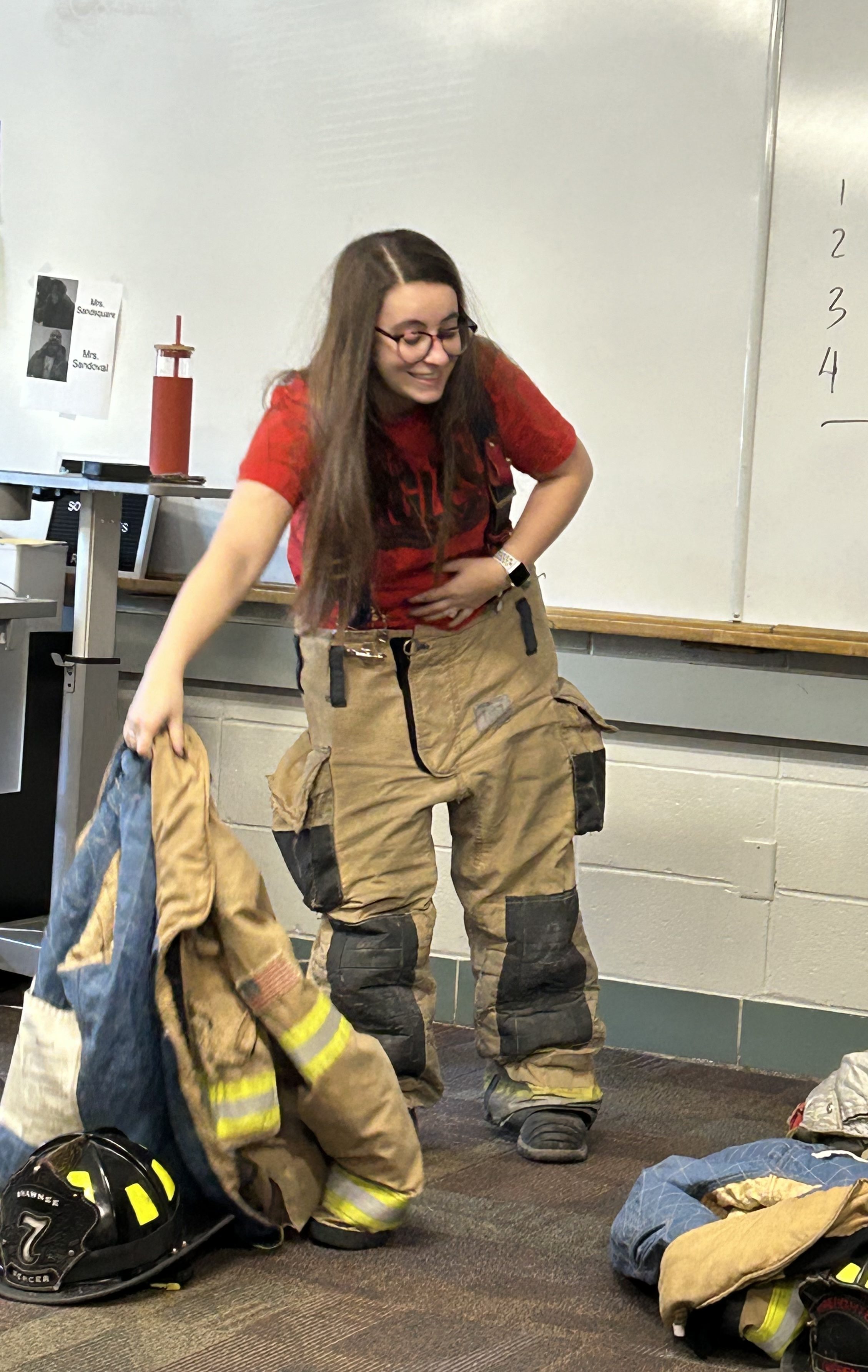Classroom scene with individuals putting on firefighter gear